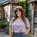 a woman in a plus size outfit of a flowy shirt and jeans with a straw hat
